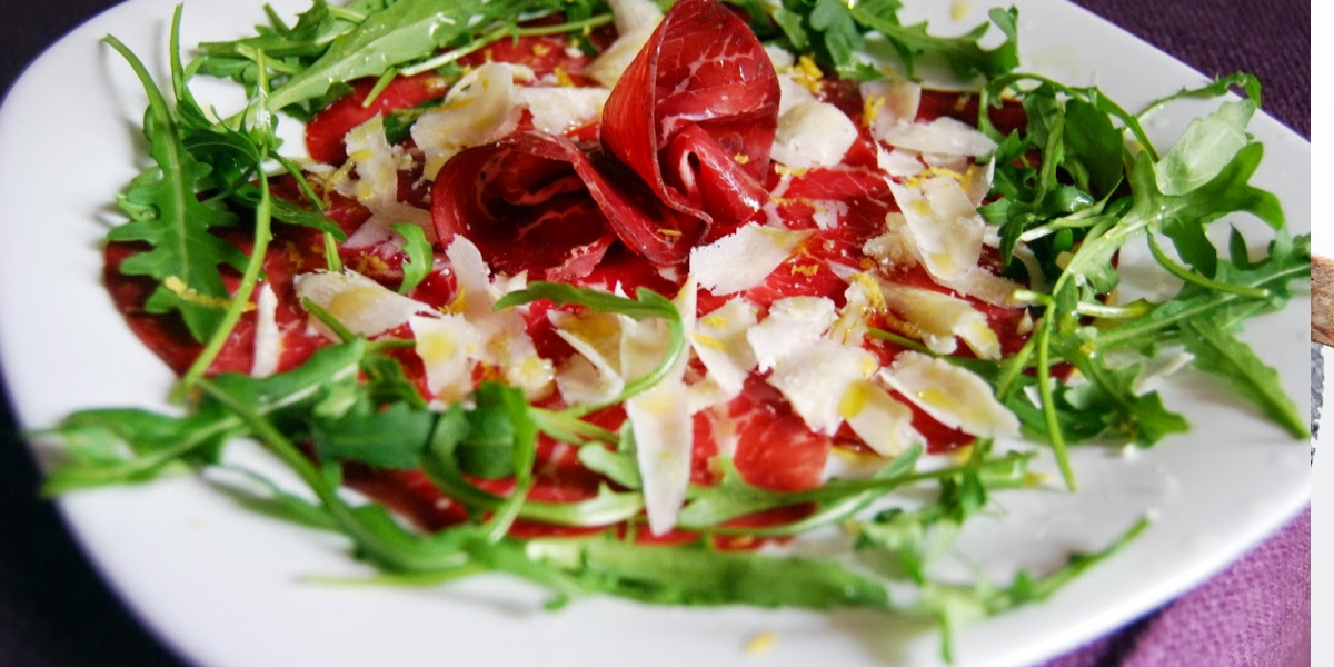 Slices of bresaola air dried beef served with rocket salad 